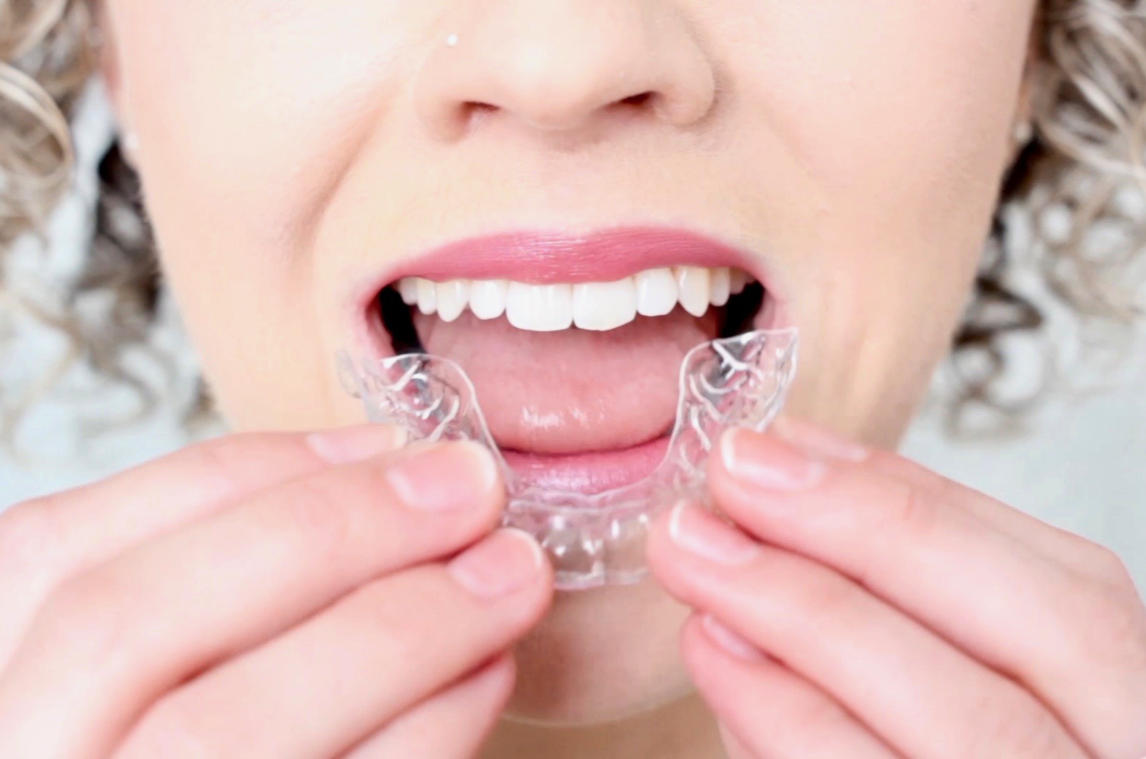 Woman holding Smilelign clear aligners.